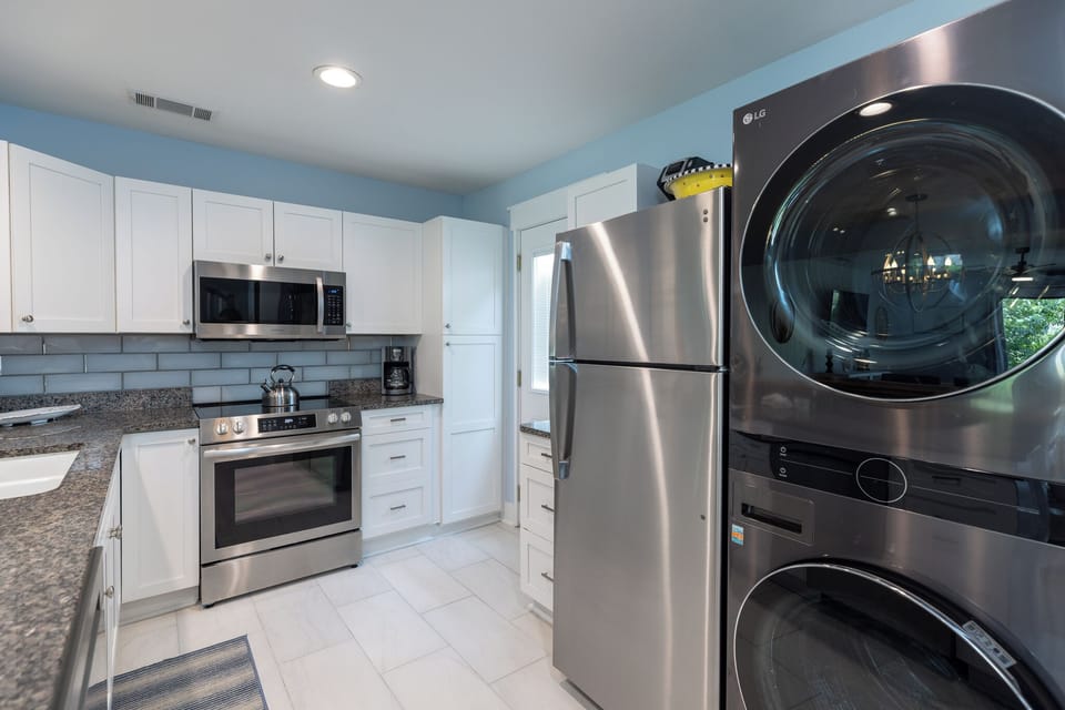 Modern kitchen with stainless steel appliances and white cabinetry with a washer and dryer