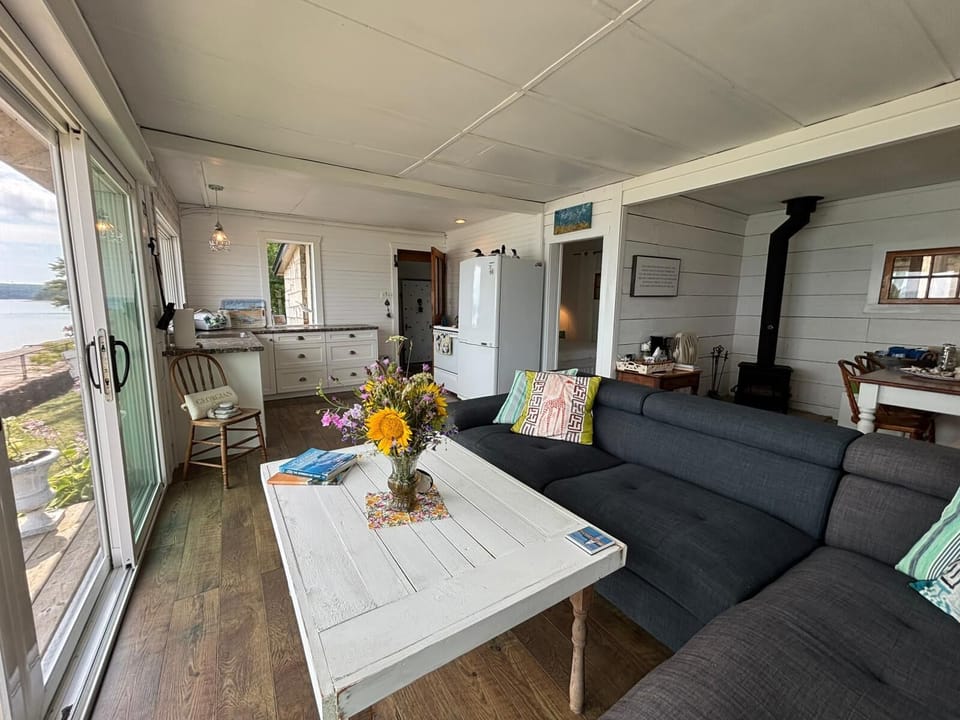 Open-concept lounge with large windows, comfy seating, and direct access to the kitchen.
