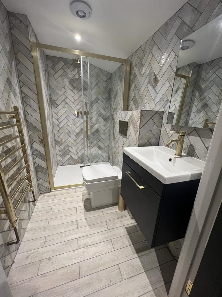 Step into luxury in the Wordsworth Apartment's bathroom, featuring Italian tiles, underfloor heating, an illuminated heated mirror, a brushed brass towel rail, and a refreshing rainfall shower.