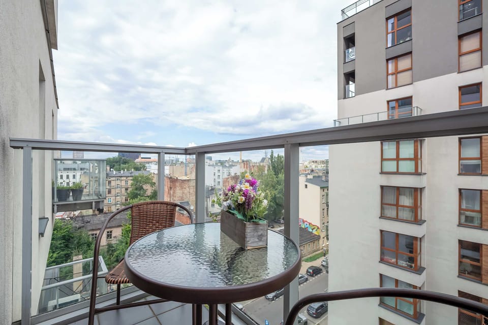Flowers on the table and a view of modern buildings create a cozy balcony spot for enjoying fresh air.