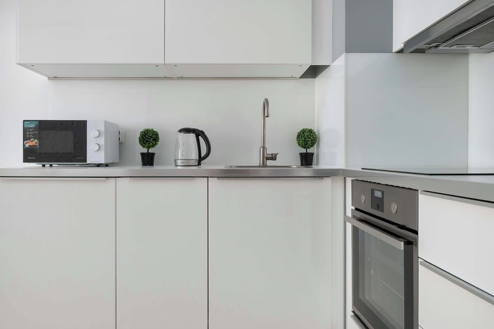 The modern white kitchen is fully equipped with all essential appliances, making meal preparation a real pleasure.

