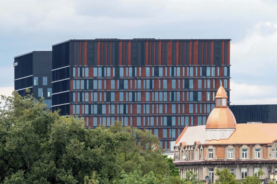 The view of a colorful office building and city skyline adds vibrancy and urban energy to the location.

