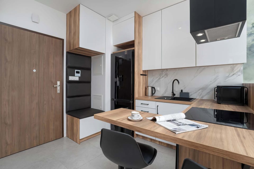 The interior impresses with its smart layout – the functional kitchenette with an extended countertop serves as both a dining and workspace, while elegant cabinetry with wooden accents highlights the apartment’s modern character.