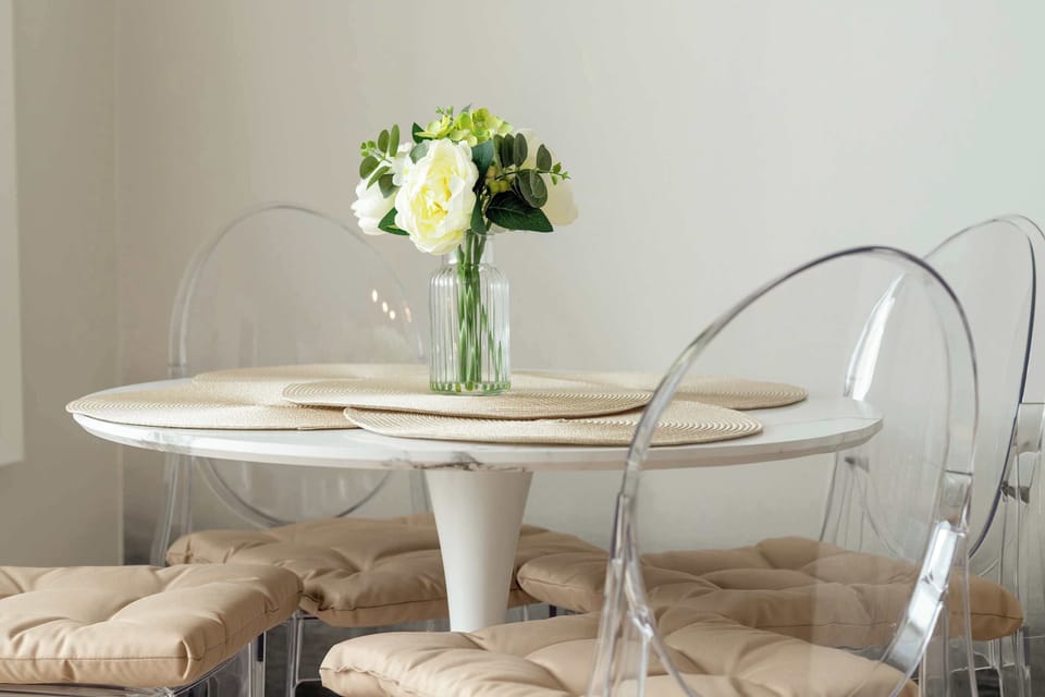 A cozy table with transparent chairs and fresh flowers creates the perfect spot for morning coffee or a romantic meal.