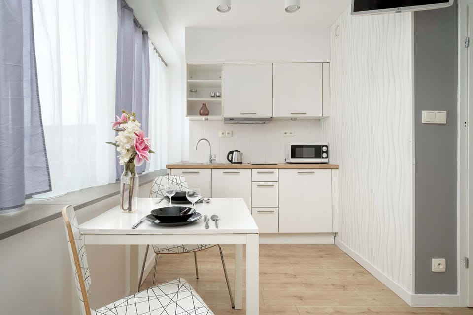 The bright kitchenette with a dining area and flowers on the table creates a homely atmosphere in the heart of the studio.