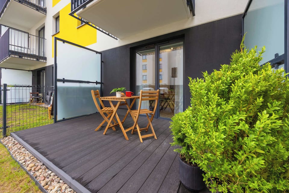 The cozy terrace with a wooden table and chairs surrounded by greenery is perfect for breakfast in the open air.

