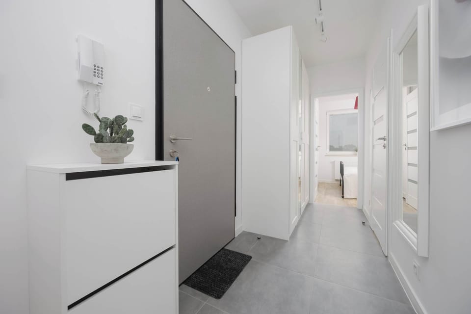 The clean, minimalist entrance area with a doormat and potted plant ensures practicality from the moment you arrive.