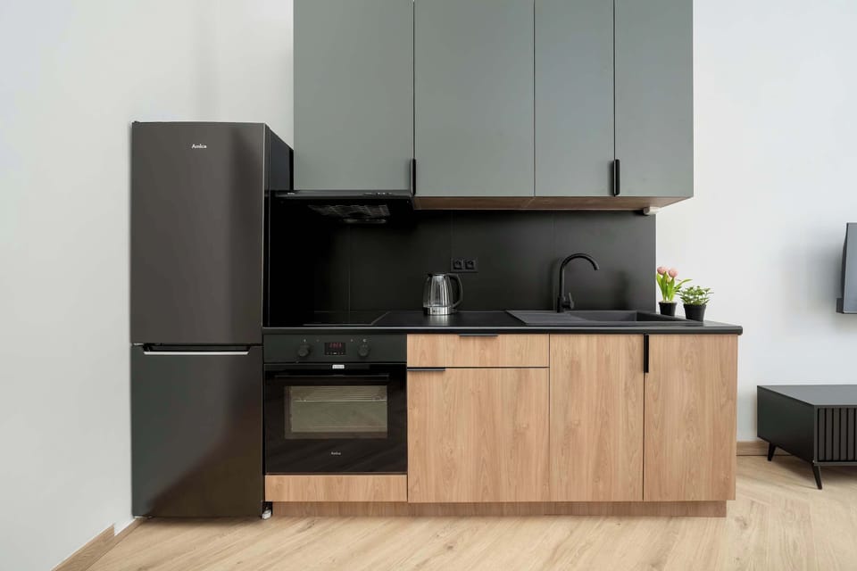 The modern kitchen with black appliances and wooden cabinetry is a perfect spot for preparing home-cooked meals.