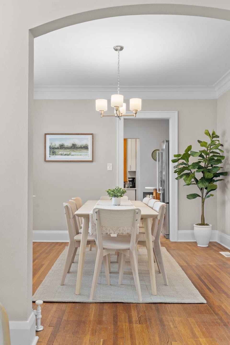 Your bright dining area features warm wood floors, elegant lighting, and fresh greenery creating the perfect spot for memorable meals together.