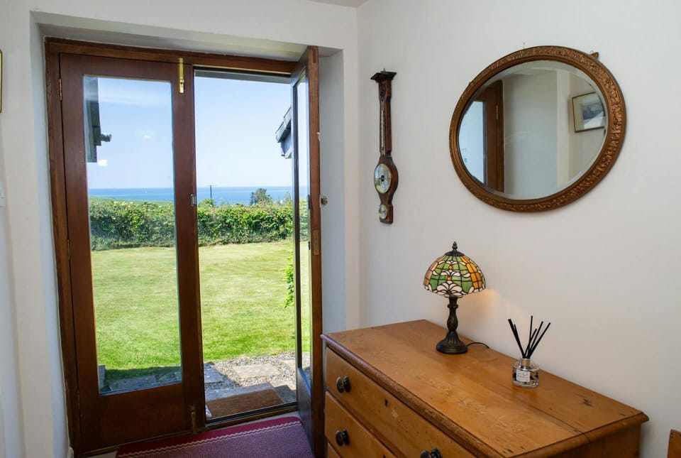 Entrance to the garden by patio doors with a chest of drawers and a lamp and mirror