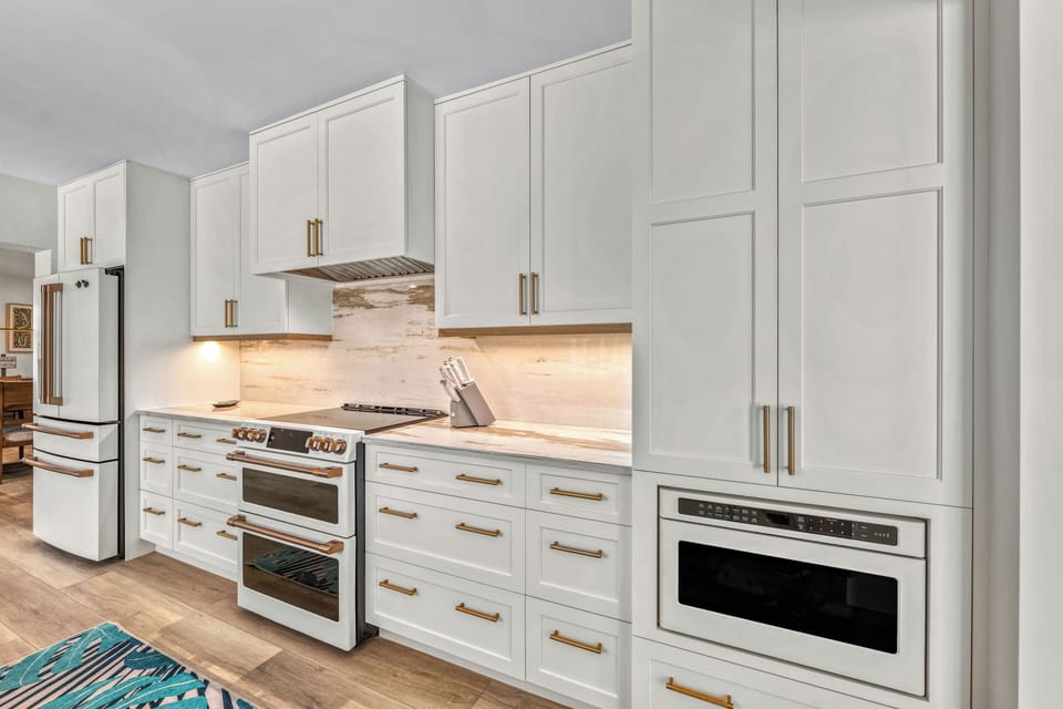This spacious kitchen flows into the heart of the home with granite counters, color accented appliances, and serene coastal energy.