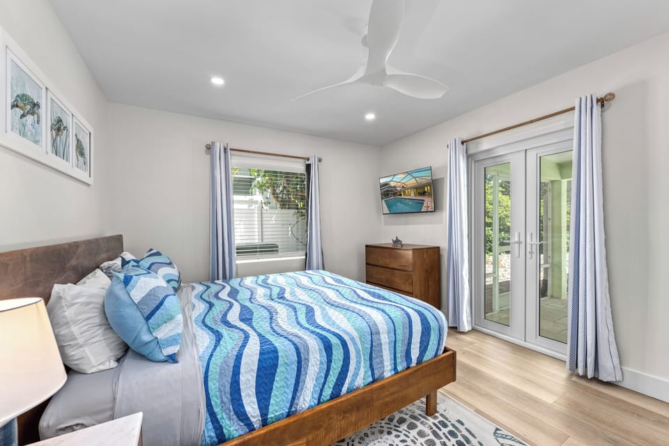 Bedroom 2, with queen bed with private access to courtyard and serene coastal decor.