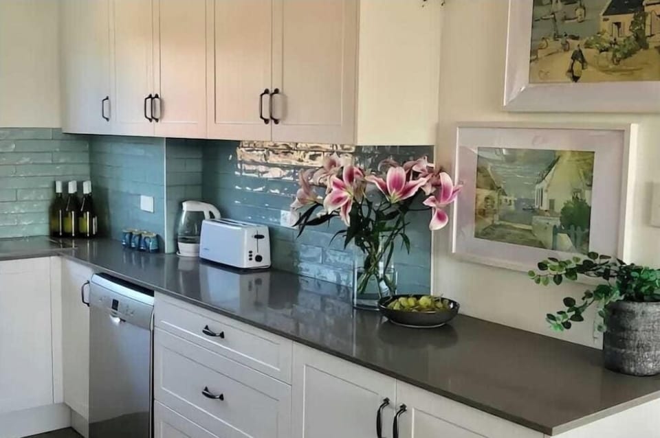A charming, fully equipped kitchen featuring pristine white cabinetry