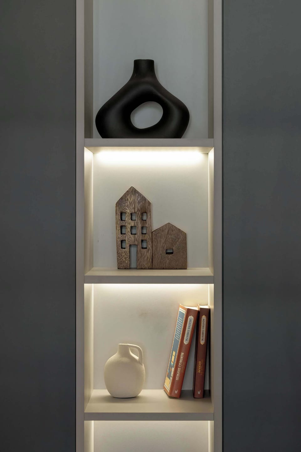 A built-in shelf with minimalist decor pieces. The soft lighting highlights the textures of the objects.