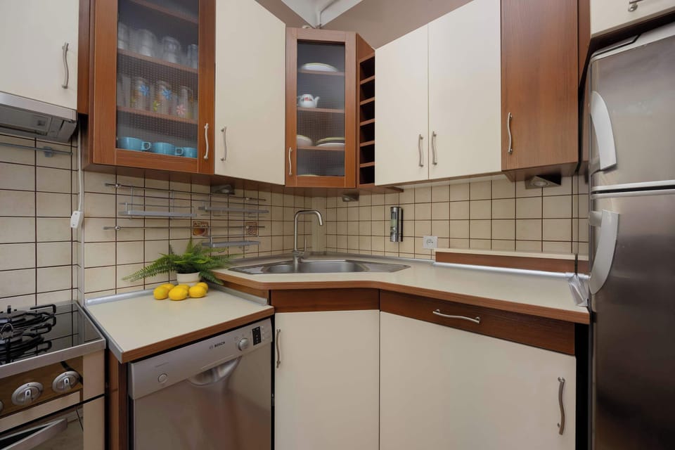 A compact kitchen corner with a stove, cabinets, and tiled backsplash.