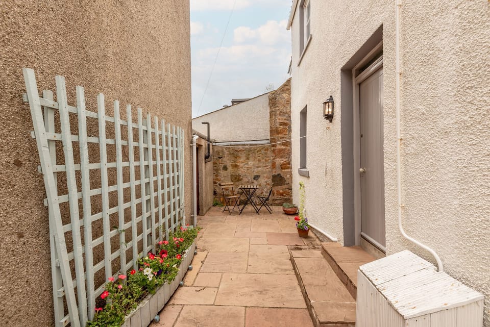 Gate and paved patio with planters beside the side door at Earls Lodge holiday cottage, Earlsferry.
