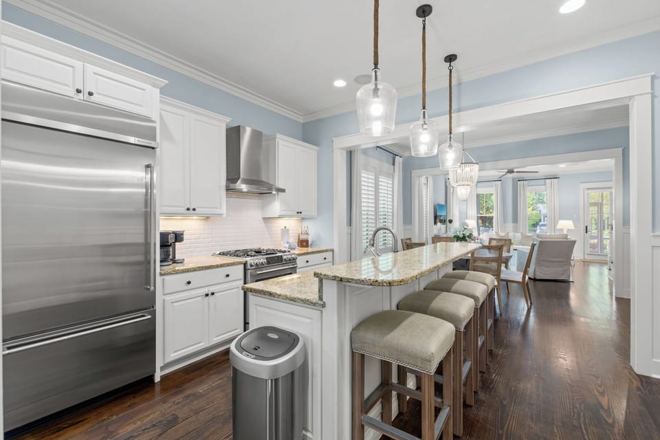 Spacious kitchen w/ granite island, bar seating & pendant lights flowing into the main living area.