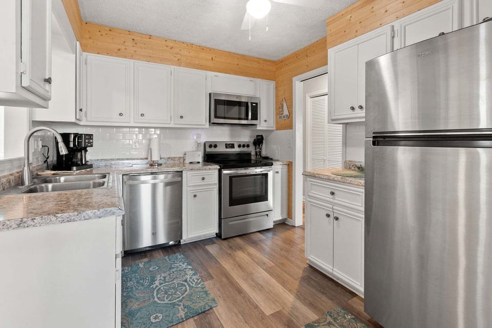 Kitchen with white cabinetry, wood-paneled walls and a full run of appliances at Wells Tales, Cherry Grove