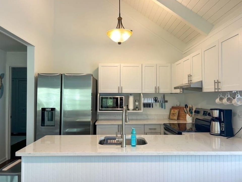 The open-concept kitchen features a large stainless steel refrigerator, microwave, and plenty of counter space.