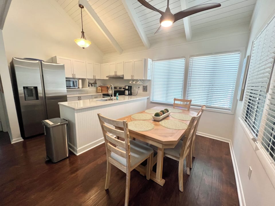 Gather for elegant meals at the bright dining table, featuring a natural wood top and stylish white chairs against shiplap paneling.
