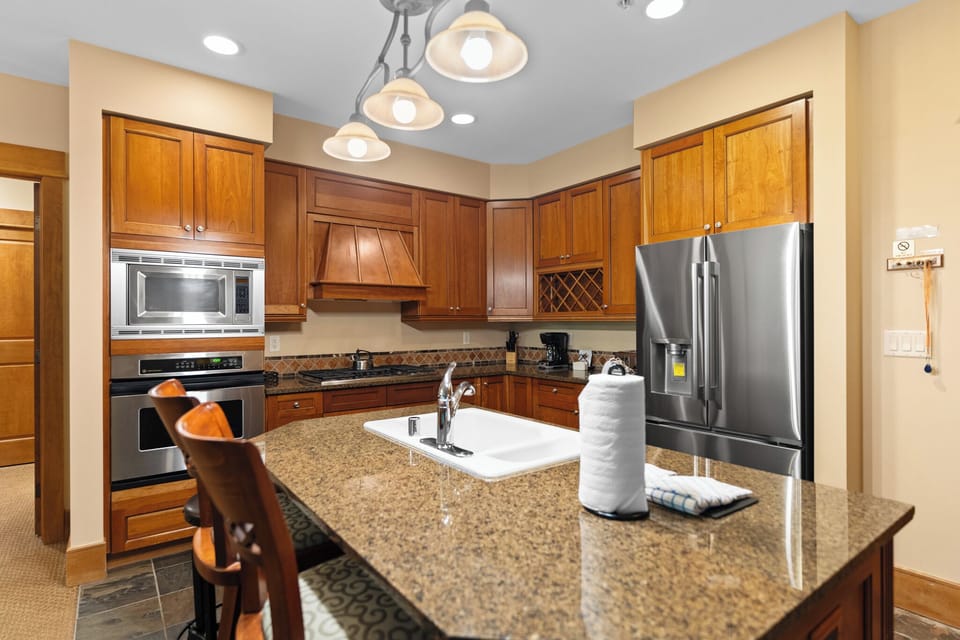 Cook your favorite meals in this fully equipped kitchen featuring granite countertops, stainless steel appliances, and warm wood cabinetry.