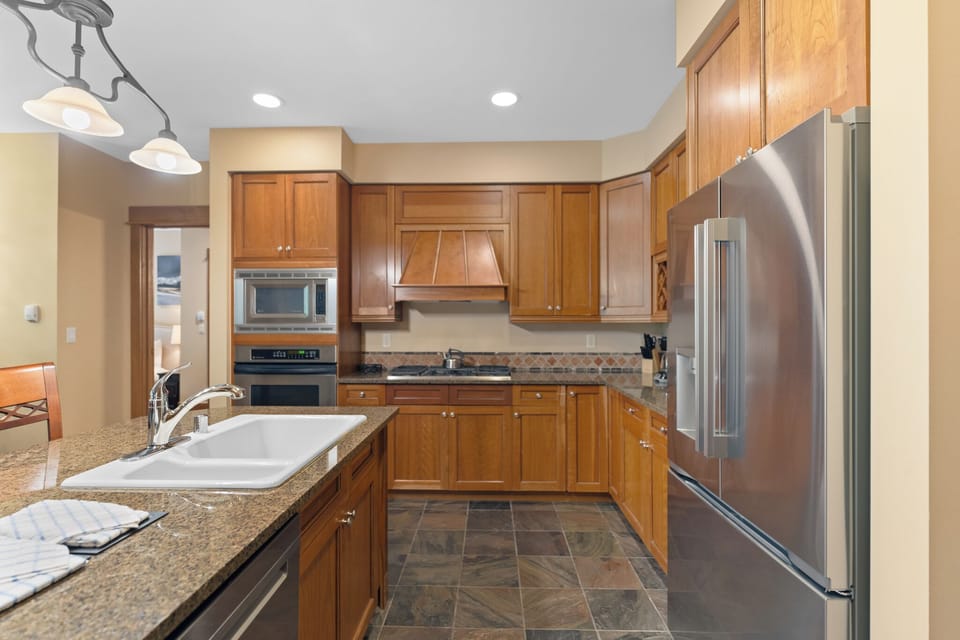 Your fully equipped kitchen awaits with granite countertops, stainless steel appliances, and warm wood cabinets—perfect for preparing memorable meals during your stay.