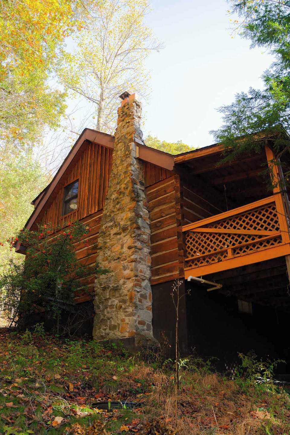 Charming Cabin Exterior: Enjoy rustic elegance with a stone chimney and vibrant nature all around!