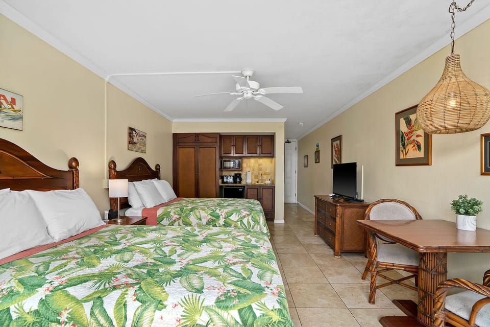 Relax in your tropical-themed studio with vibrant palm bedding, full kitchen, cozy dining nook, and warm wood furnishings.