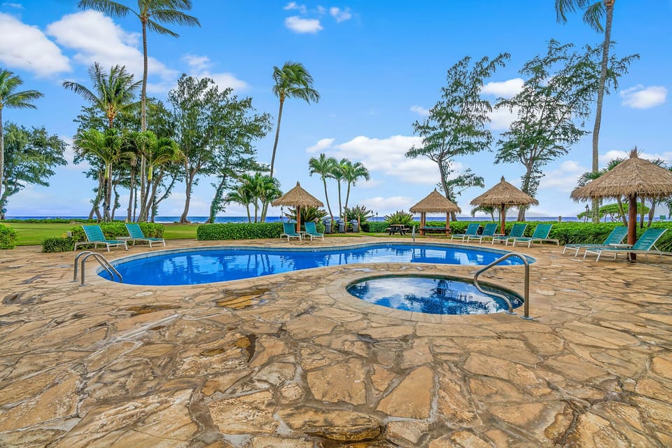 Tropical paradise pool with spa jacuzzi, thatched umbrellas, and ocean views awaits your perfect Hawaiian getaway.