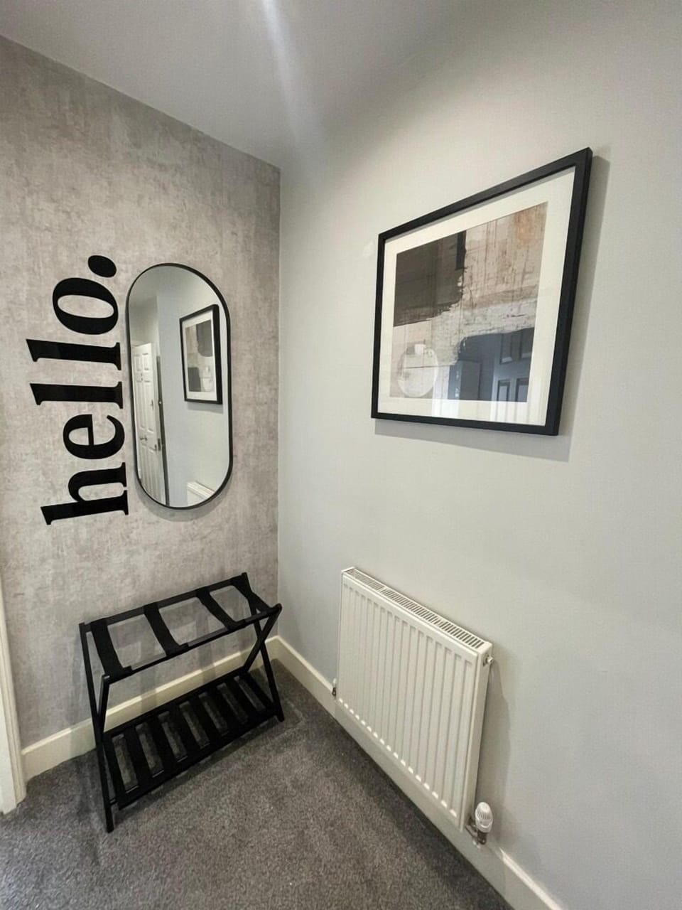 A bright hallway with a wall-mounted mirror and a convenient luggage rack, providing a practical space to settle in and organise your belongings.
