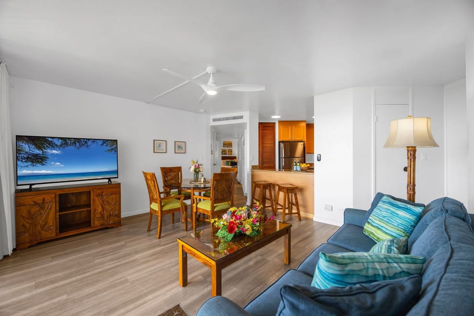 Spacious open layout with island-inspired furnishings, a large Smart TV, and breakfast bar seating just off the fully equipped kitchen.