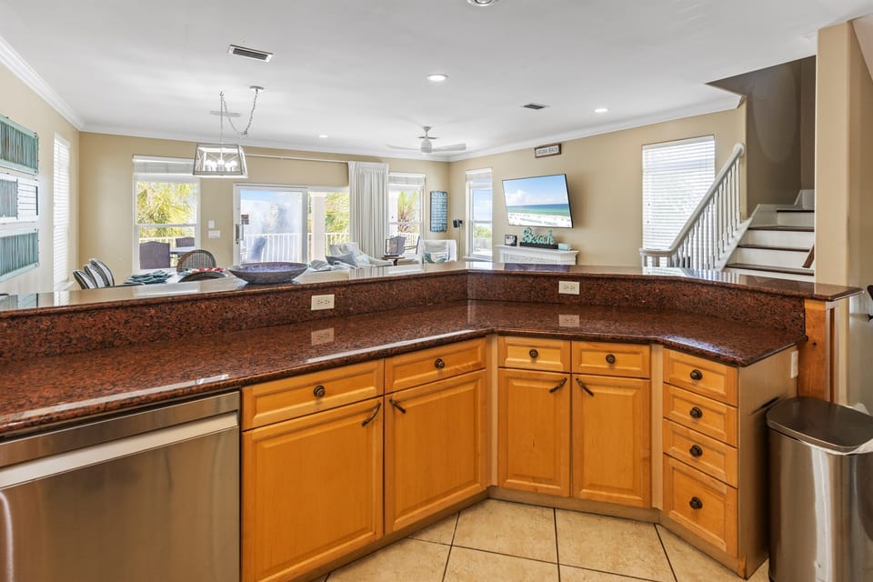 Your spacious kitchen flows seamlessly into the living area, offering granite counters and ocean views while you prepare meals.
