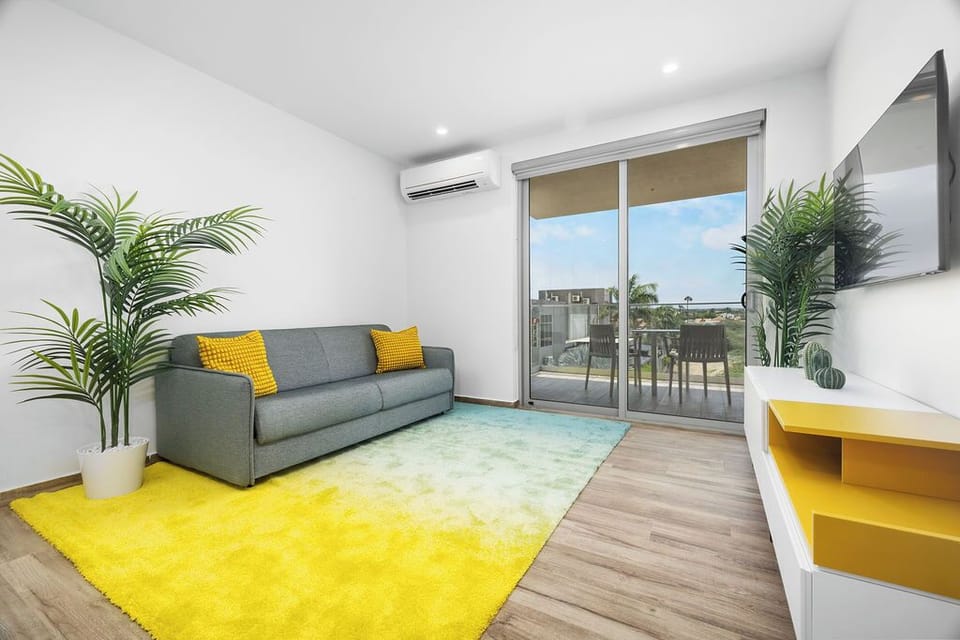 Bright and inviting living room with a comfy sofa bed, smart TV for your favorite shows, and direct access to a private balcony — the perfect space to unwind or entertain.