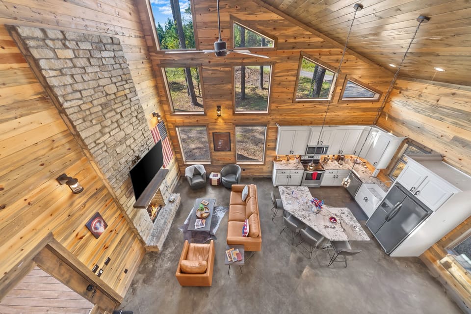 Spacious open layout with tall windows, cozy fire, and forest views