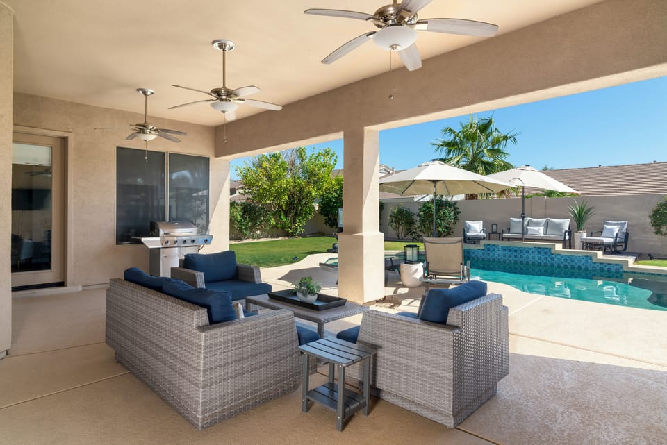 Covered outdoor living area with pool views and outdoor TV