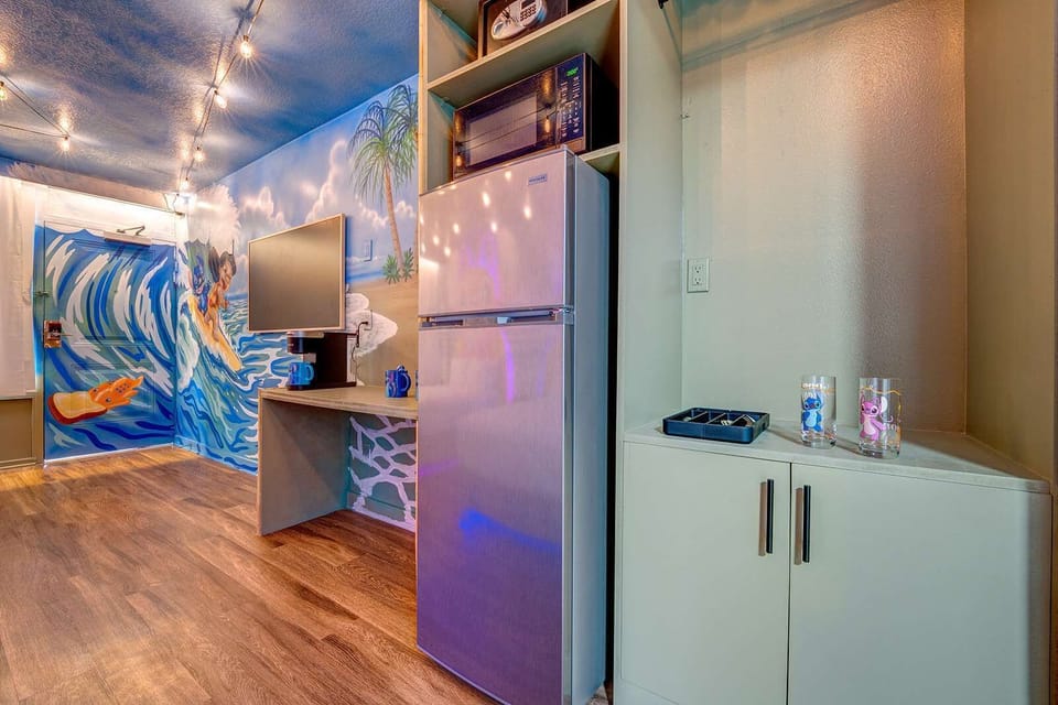Modern kitchenette area with a stainless steel refrigerator and colorful mural wall art.