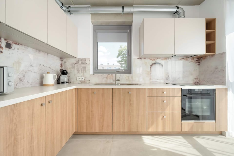 A modern kitchenette with built-in appliances and wooden cabinets. Fully equipped for everyday cooking.