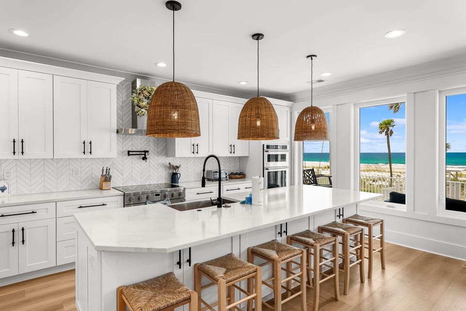 Your gourmet kitchen showcases stunning ocean views through floor-to-ceiling windows, creating the perfect backdrop for memorable meals.
