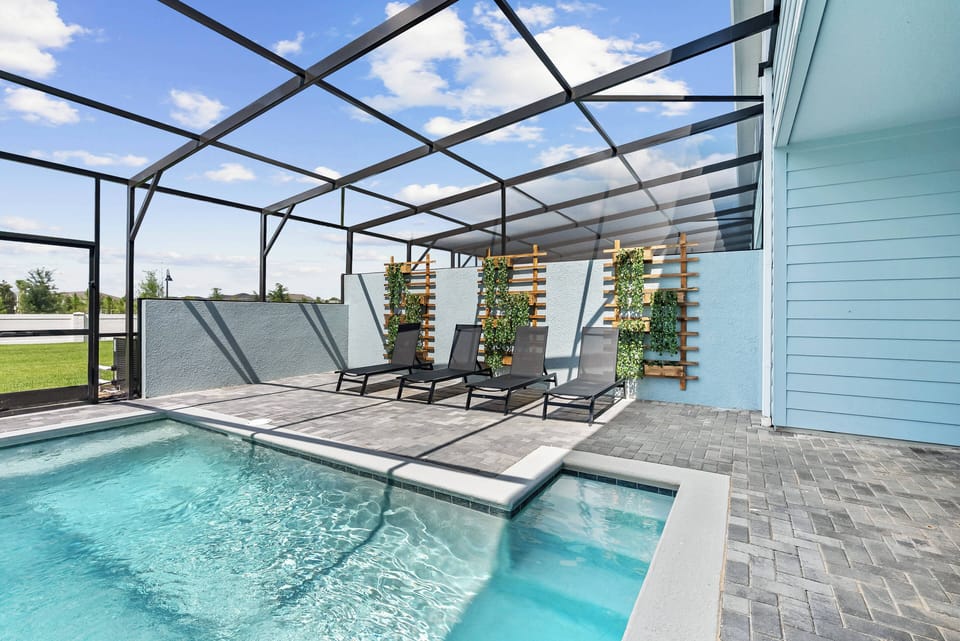 Step outside to your private oasis, where a sleek, sparkling pool awaits under a stylish screened enclosure. Relax on the modern loungers surrounded by lush greenery, all set against a backdrop of clear blue skies.
