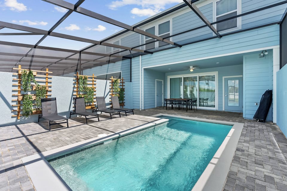Step outside to enjoy a refreshing dip in your private pool, surrounded by charming greenery and sleek loungers. The light blue walls and airy layout create a bright, cheerful atmosphere that invites relaxation and fun.