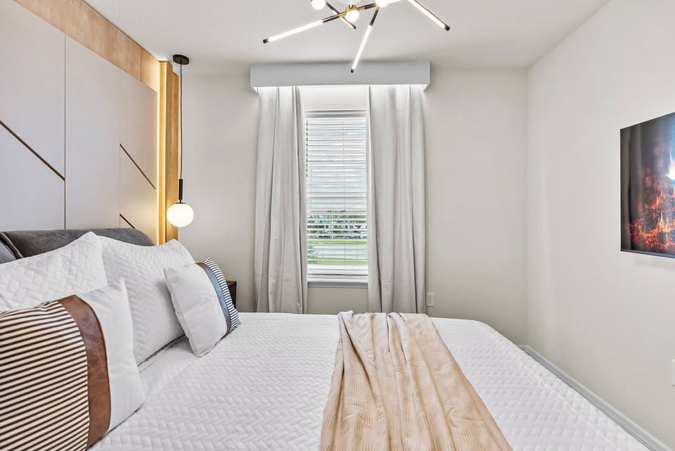 Unwind in this beautifully designed bedroom with a plush king-sized bed adorned with textured linens and decorative pillows. Bask in the soft natural light streaming through the drapes, accentuating the contemporary art and.