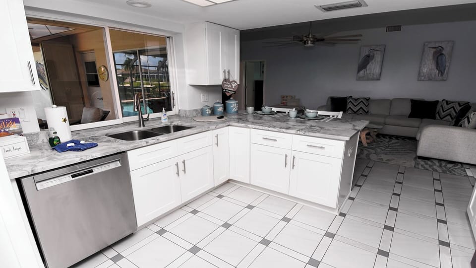 Bright kitchen with elegant marble countertops and view of patio and pool