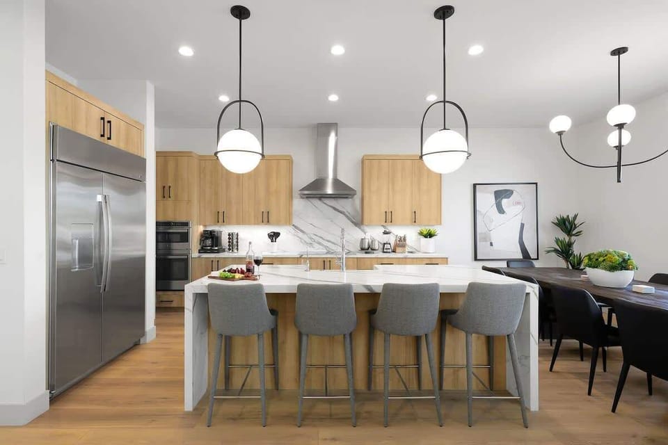 Fully equipped kitchen with stainless steel appliances, a sleek kitchen island with a breakfast bar for casual seating for 4, plus a large dining table for 10. (1st Floor)