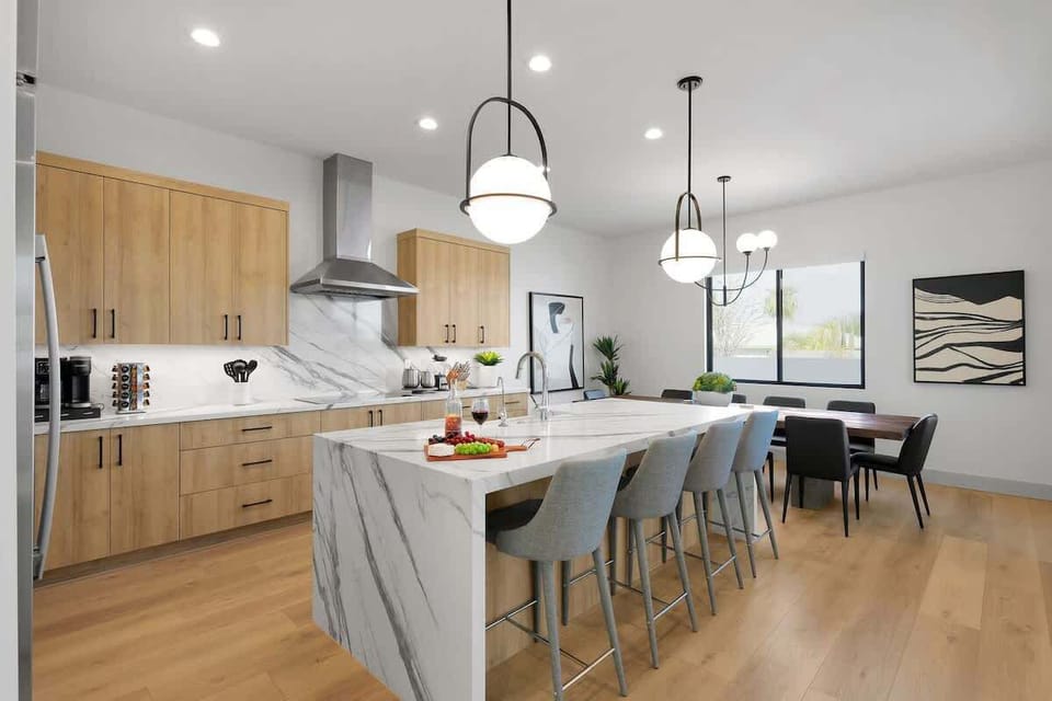 Fully equipped kitchen with stainless steel appliances, a sleek kitchen island with a breakfast bar for casual seating for 4, plus a large dining table for 10. (1st Floor)