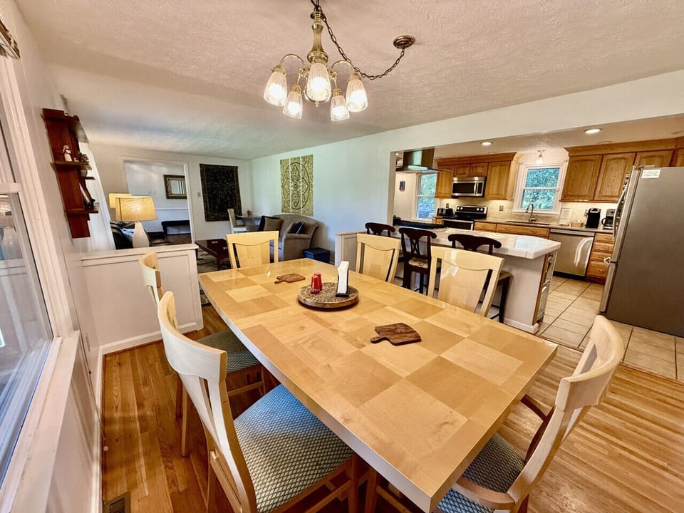 Dining room with large wooden table and chandelier lighting.