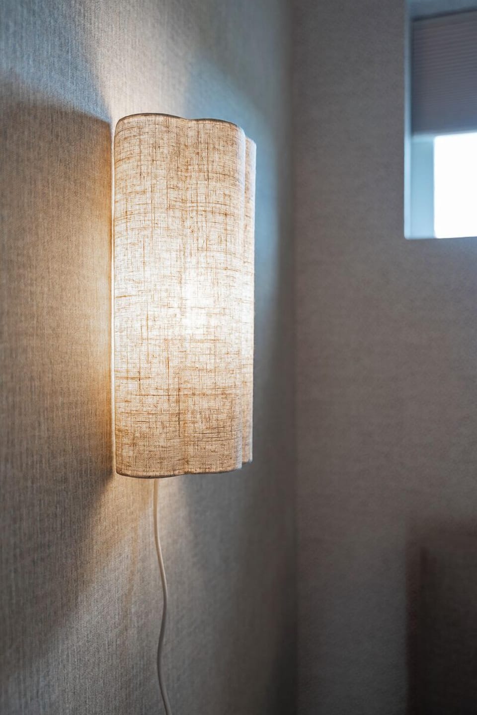 Soft ambient light from a modern wall lamp creates a warm, inviting atmosphere for restful evenings.