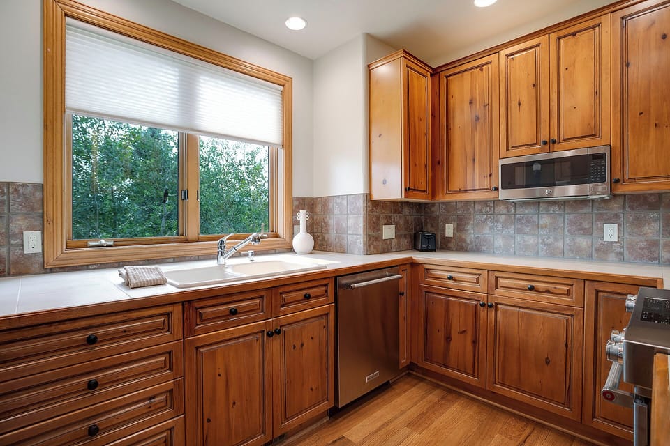 Your fully equipped kitchen features warm wood cabinetry, modern appliances, and a garden view window perfect for morning coffee prep.