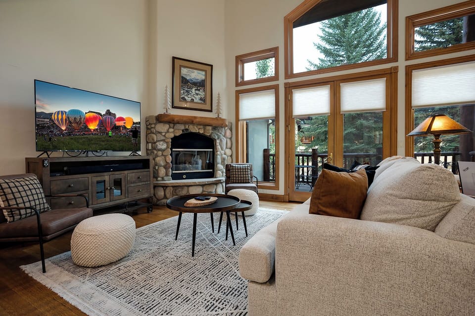 Sink into plush sofas by your stone fireplace while watching the big screen, surrounded by warm wood accents and forest views.