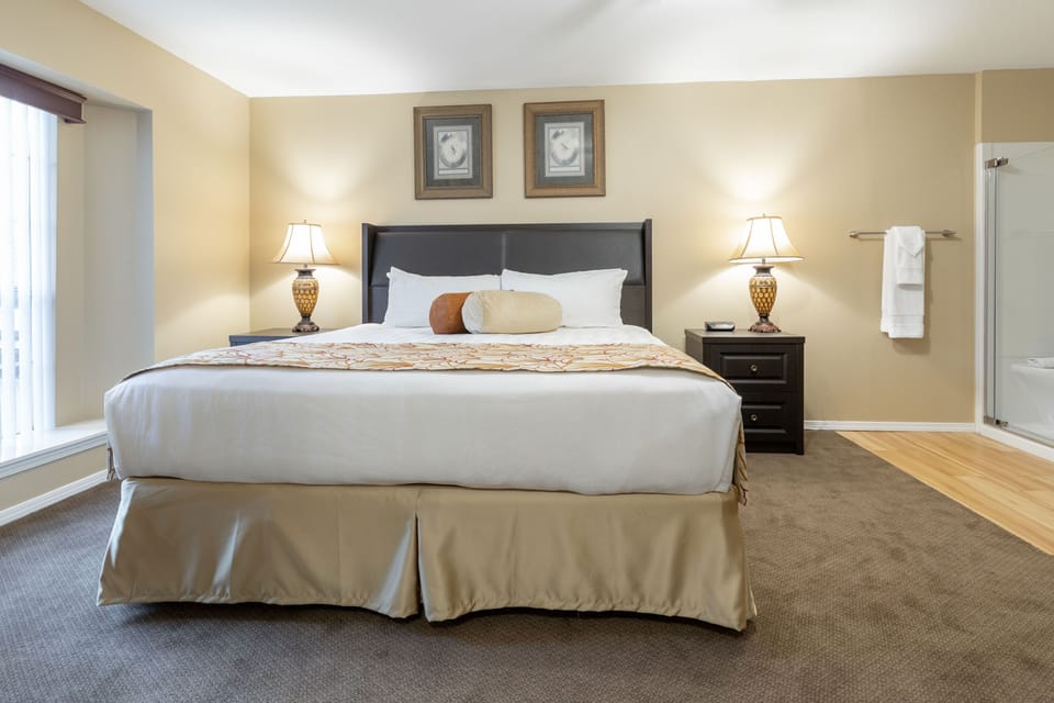 The master bedroom features a king bed with elegant linens, soft lighting, and relaxing artwork.