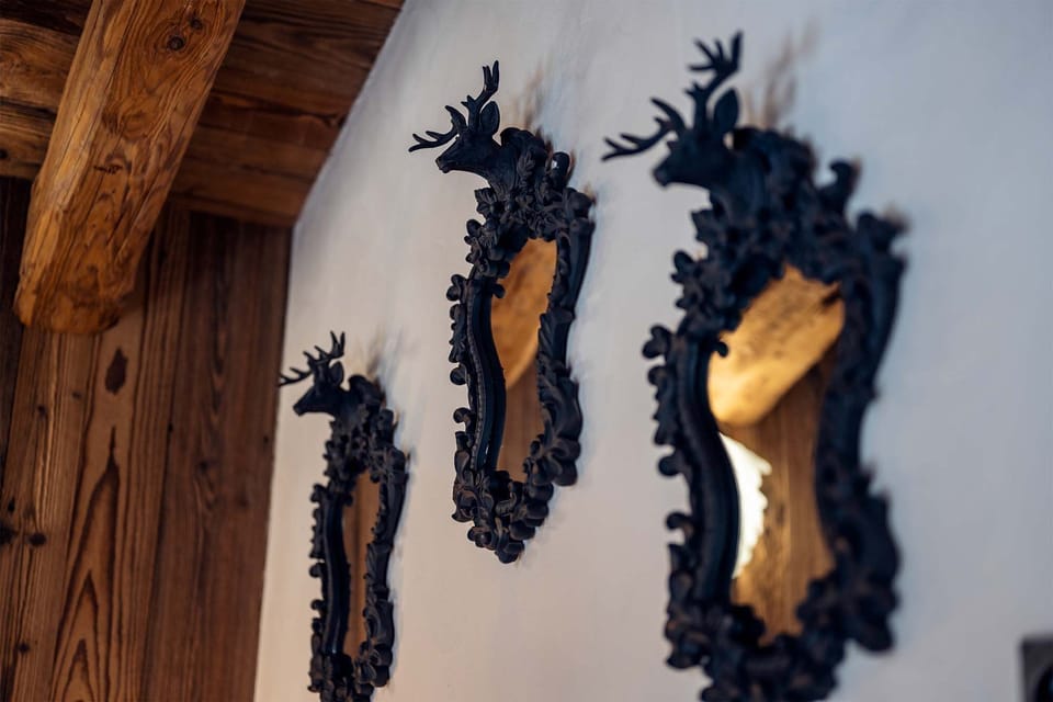 Exquisite alpine-themed mirrors reflect the chalet’s rich craftsmanship, enhancing the charming ambiance throughout the luxurious spaces.